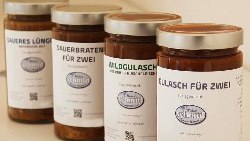 Vier Gläser mit fertigen Gerichten wie Gulasch & Sauerbraten für zwei Personen, mit Etikett der Metzgerei Schmid